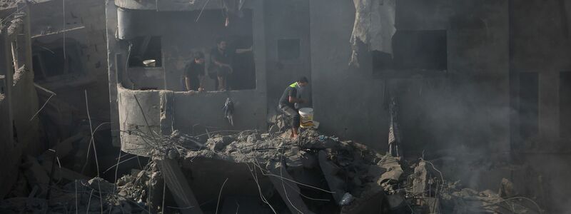 Palästinenser suchen in den Trümmern eines zerstörten Gebäudes in Bureij nach Überlebenden. - Foto: Mohammed Dahman/AP/dpa