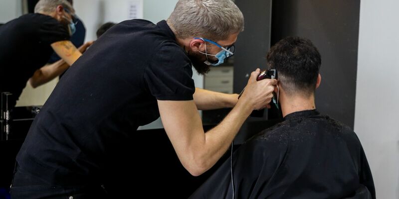 Ein Friseur schneidet die Haare eines Kunden in einem Friseursalon. - Foto: Ricardo Rubio/Europa Press/dpa
