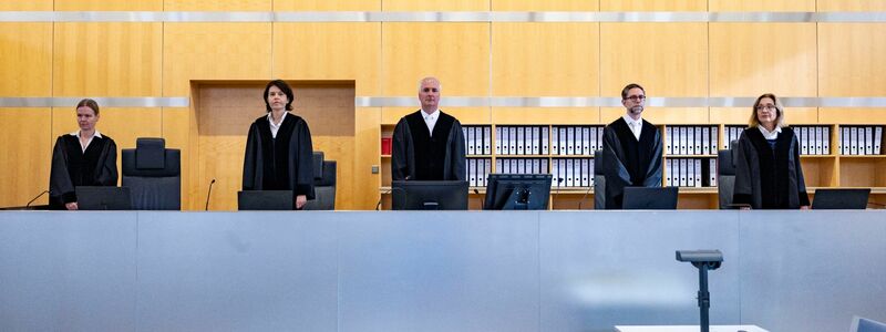 Der Richtertisch mit Jan van Lessen (M), dem Vorsitzenden Richter am Oberlandesgericht. - Foto: Christoph Reichwein/dpa