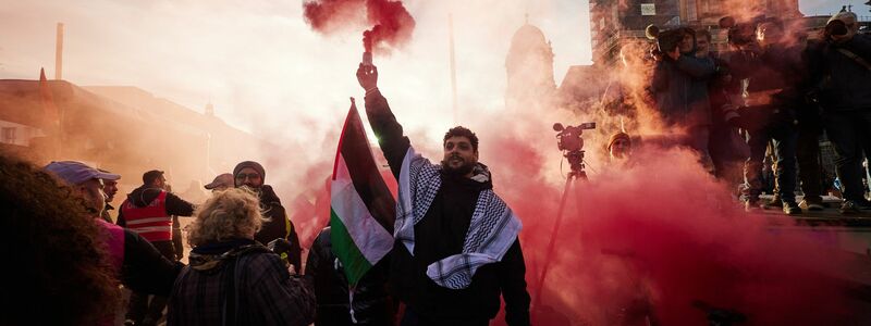 Teilnehmer einer Pro-Palästina-Kundgebung auf der Straße Unter den Linden zünden Pyrotechnik. - Foto: Jörg Carstensen/dpa