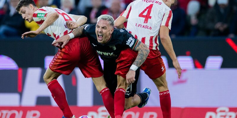 Die Kölner Eric Martel (l) und Timo Hübers (r) nehmen Augsburgs Philipp Tietz in die Zange. - Foto: Rolf Vennenbernd/dpa