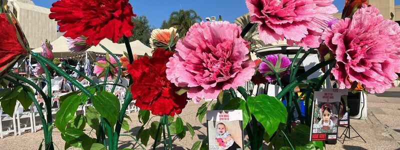 Blumen mit Bildern von Kindern, die seit dem Massaker der Hamas im israelischen Grenzgebiet am 07. Oktober als Geiseln gehalten und vermisst werden, stehen vor dem Kunstmuseum in Tel Aviv. - Foto: Sara Lemel/dpa