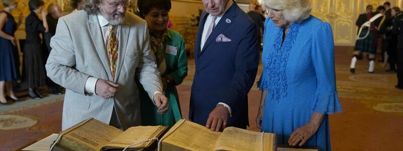 König Charles III. und Königin Camilla betrachten das erste Shakespeare-Folio während eines Empfangs auf Schloss Windsor. - Foto: Andrew Matthews/PA Wire/dpa