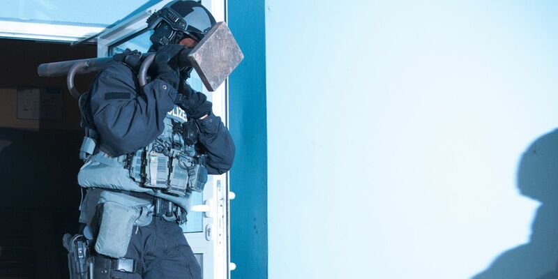 Ein Polizist verlässt bei einer Razzia ein Haus in Berlin. - Foto: Paul Zinken/dpa