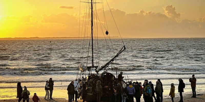 Ein am Weststrand der Insel Norderney gestrandetes Segelschiff mit Schaulustigen. - Foto: Volker Bartels/dpa