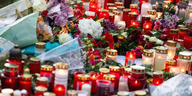 Blumen und Kerzen liegen während einer stillen Gedenkveranstaltung vor der Schule. - Foto: Philipp von Ditfurth/dpa