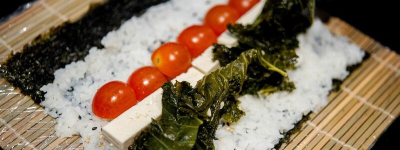 Ein Koch bereitet in der Küche des Restaurants Moto Kitchen Sushi mit Grünkohl, Tomaten und Feta zu. - Foto: Hauke-Christian Dittrich/dpa