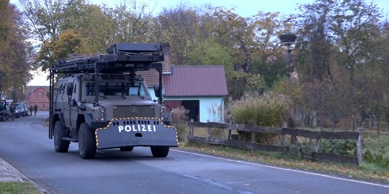 Schweres Gerät eines Spezialeinsatzkommandos der Polizei rollt durch den Ort. Nach Schüssen einer bewaffneten Person mit einem Kind auf die Polizei dauert der Einsatz im Landkreis Havelland nach rund 20 Stunden noch an. - Foto: Cevin Dettlaff/TNN/dpa