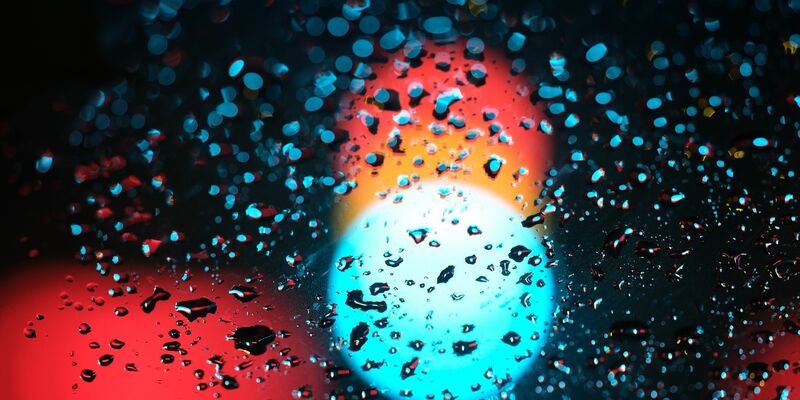 Eine Ampel hinter einer regennassen Scheibe eines Autos. - Foto: Sebastian Willnow/dpa