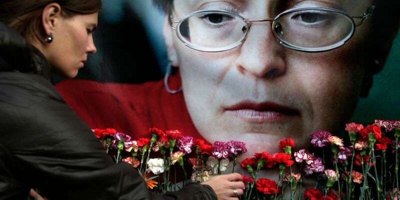 Eine Frau legt in Moskau Blumen vor einem Porträt der ermordeten russischen Journalistin Anna Politkowskaja nieder (Archivbild). - Foto: Pavel Golovkin/AP/dpa