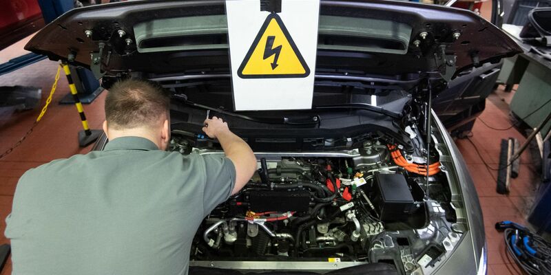 Ein KFZ-Mechaniker wartet ein E-Auto. - Foto: Marijan Murat/dpa