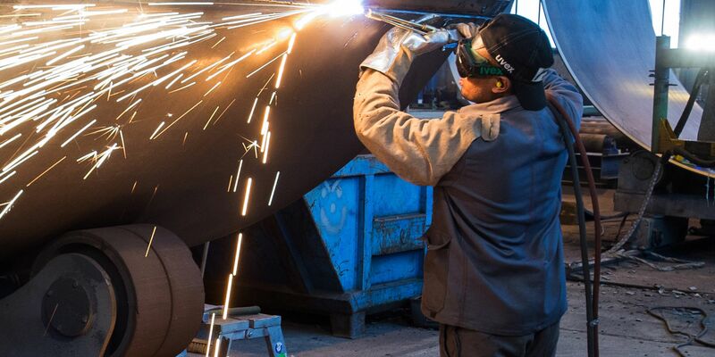 Ein Mann aus Somalia, der zuvor als Schweißer ausgebildet wurde, arbeitet in einer Firma an einem Stahlsegment. - Foto: Patrick Pleul/ZB/dpa