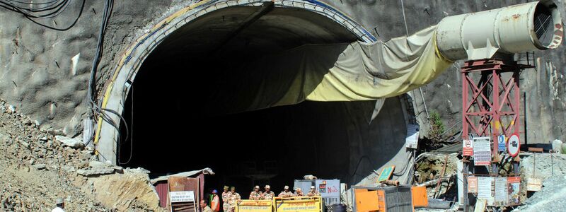 Menschen beobachten Rettungs- und Hilfsmaßnahmen an der Stelle eines im Bau befindlichen Straßentunnels, der im indischen Bundesstaat Uttarakhand eingestürzt ist. - Foto: Uncredited/AP/dpa