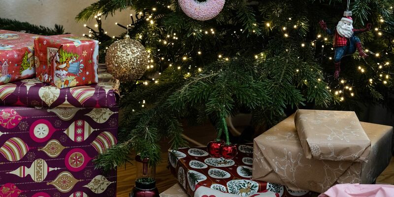 Eingepackte Geschenke liegen unter einem geschmückten Weihnachtsbaum. Die Menschen in Deutschland wollen in diesem Jahr bei den Präsenten sparsamer sein. - Foto: Swen Pförtner/dpa