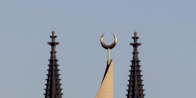 Der Halbmond auf einer Moschee ist zwischen den Türmen des Kölner Doms zu sehen. Der Auftritt eines hochrangigen afghanischen Taliban-Funktionärs in einer Kölner Moschee löst harsche Kritik aus. - Foto: Rolf Vennenbernd/dpa
