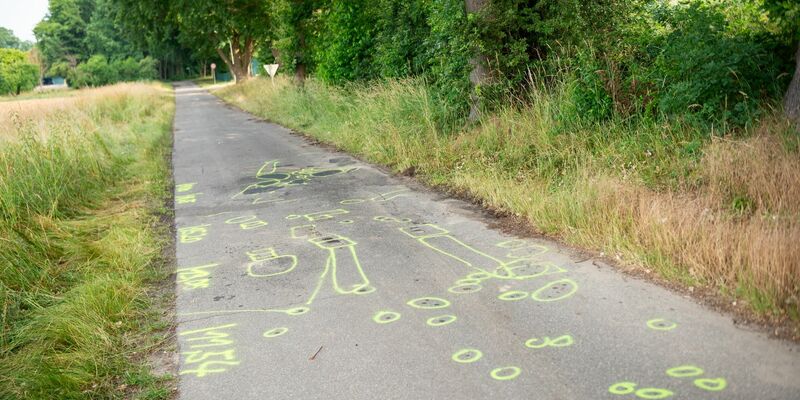 Markierungen der Polizei auf der Straße am Unfallort. - Foto: Jonas Walzberg/dpa