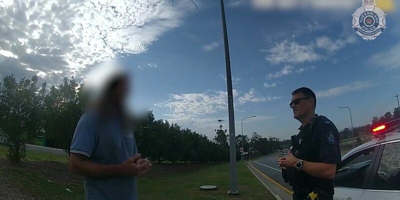 Ein Videostandbild der Polizei Queensland zeigt den Mann im Gespräch mit einem Beamten. - Foto: Queensland Police/QUEENSLAND POLICE/AP/dpa