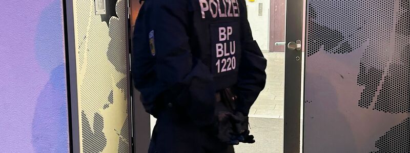 Ein Polizeibeamter steht bei einer Razzia in Berlin-Adlershof vor einem Gebäude. - Foto: Sven Kaeuler/dpa