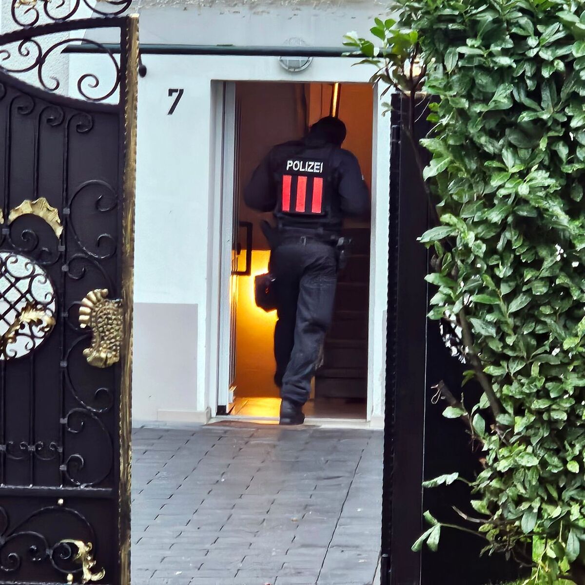 Ein Polizeibeamter geht bei einer Razzia in Bochum-Weitmar durch den Eingang eines Wohnhauses. - Foto: Markus Gayk/News Essen/dpa