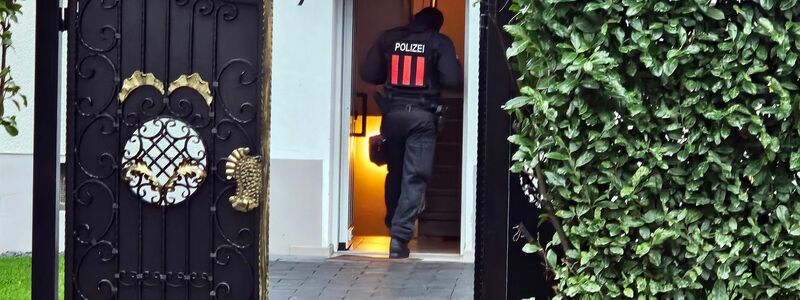 Ein Polizeibeamter geht bei einer Razzia in Bochum-Weitmar durch den Eingang eines Wohnhauses. - Foto: Markus Gayk/News Essen/dpa