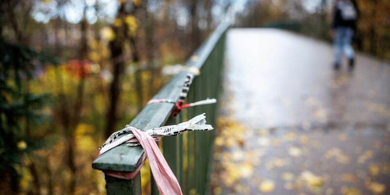 Der Rest eines Absperrbands der Polizei am Geländer einer Fußgängerbrücke im Englischen Garten in München. Dort kam das Opfer zu Tode. - Foto: Matthias Balk/dpa