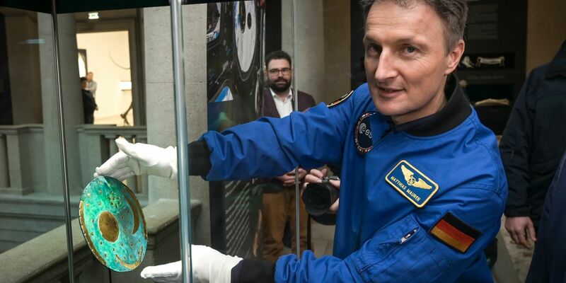 Der Astronaut Matthias Maurer platziert die Nachbildung der Himmelsscheibe von Nebra in einer Vitrine im Landesmuseum für Vorgeschichte Halle. - Foto: Heiko Rebsch/dpa