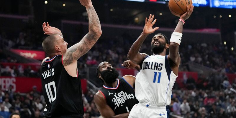 Kyrie Irving (r) von den Dallas Mavericks wirft unter dem Druck von James Harden (M) und Daniel Theis von den Los Angeles Clippers. - Foto: Jae C. Hong/AP/dpa