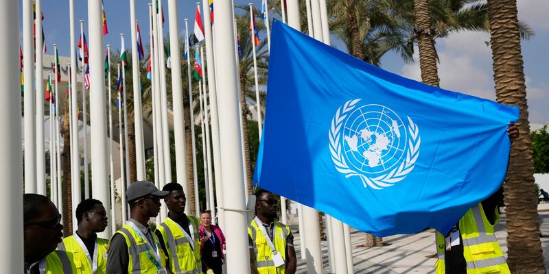 Die Flagge der Vereinten Nationen wird vor dem UN-Klimagipfel COP28 aufgehangen. - Foto: Rafiq Maqbool/AP/dpa