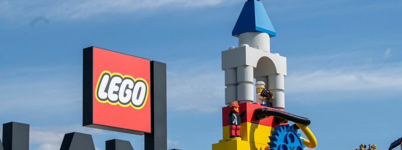 Neben dem Logo am Eingang zum Legoland ist eine Achterbahn zu sehen. - Foto: Stefan Puchner/dpa