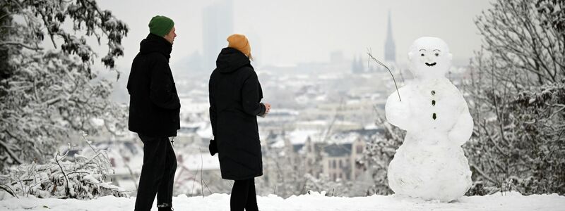 Zwei Spaziergänger wandern am Fockeberg (Leipzig) an einem Schneemann vorbei. - Foto: Patricia Bartos/dpa