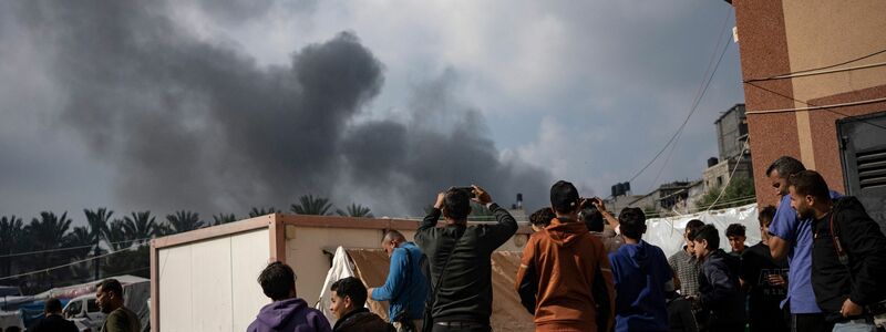 Palästinenser in Chan Junis betrachten den aufsteigenden Rauch nach einem israelischen Luftangriff. - Foto: Fatima Shbair/AP/dpa