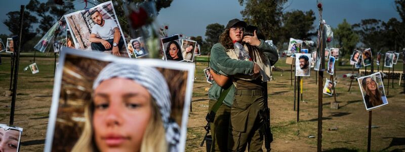 Israelische Soldatinnen stehen zwischen Fotos getöteter Israelis am Ort des Massakers beim Re'im-Musikfestival in der Negev-Wüste. - Foto: Ilia Yefimovich/dpa