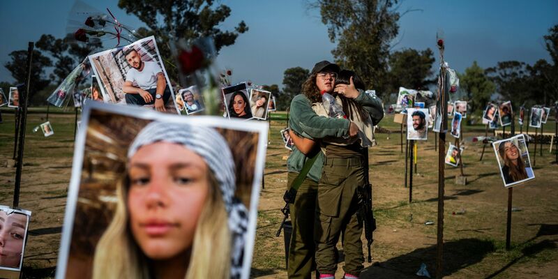Israelische Soldatinnen stehen zwischen Fotos getöteter Israelis am Ort des Massakers beim Re'im-Musikfestival in der Negev-Wüste. - Foto: Ilia Yefimovich/dpa