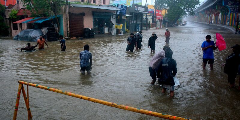 Menschen waten durch eine überschwemmte Straße nach heftigen Regenfällen an der Küste des Golfs von Bengalen. - Foto: Uncredited/AP