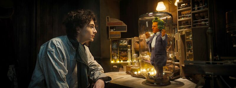 Timothée Chalamet (l) als Willy Wonka und Hugh Grant als Oompa Loompa in einer Szene des Films «Wonka». - Foto: Warner Bros. Picture/dpa