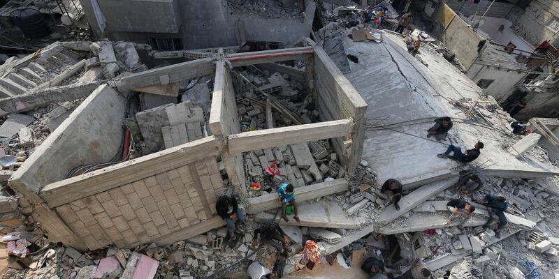 Palästinenser suchen in einem zerstörten Flüchtlingslager im Zentrum des Gazastreifens nach Leichen. - Foto: Adel Hana/AP/dpa