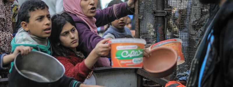 Menschen bitten an einer Essensausgabe in Rafah um Lebensmittel. - Foto: Mohammed Talatene/dpa