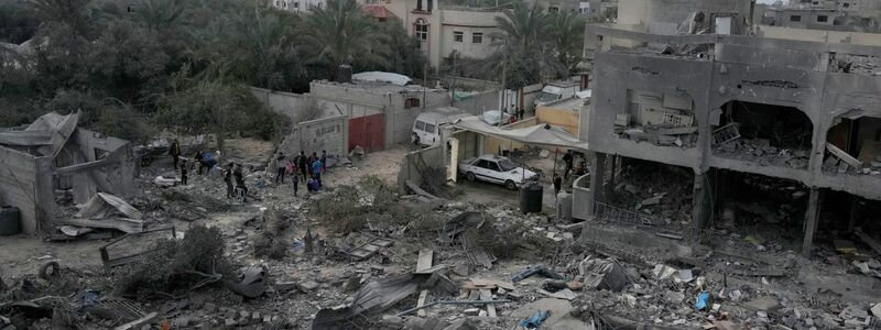 Palästinenser betrachten die Trümmer eines Gebäudes im Zenrum des Gazastreifens, das bei einer israelischen Bombardierung zerstört wurde. - Foto: Hatem Moussa/AP/dpa