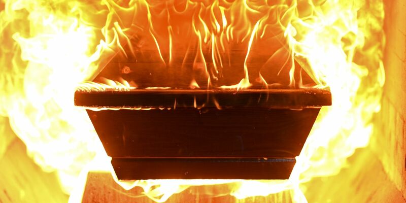 Ein Sarg fängt Feuer, nachdem er in den Ofen des Krematoriums hineingefahren wurde. - Foto: Felix Kästle/dpa