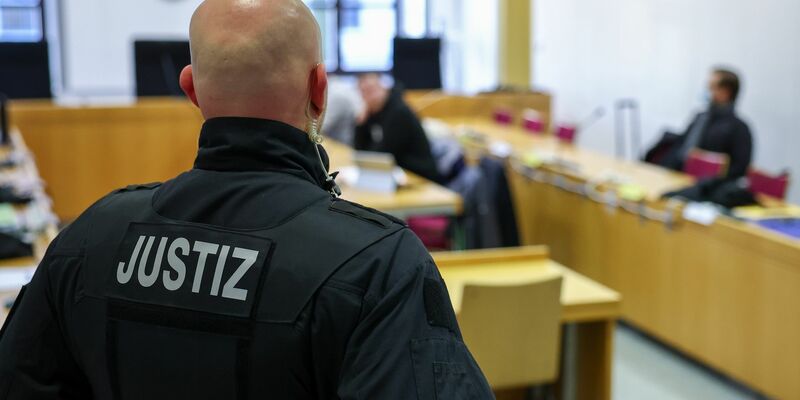 Ein Justizbeamter steht vor Prozessbeginn vor einigen Angeklagten im Landgericht Chemnitz. - Foto: Jan Woitas/dpa