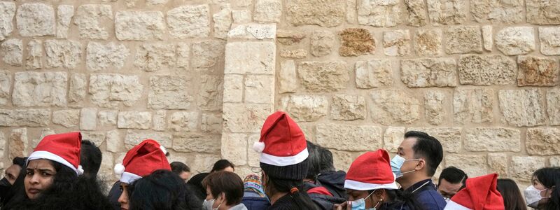 Heiligabend im vergangenen Jahr: Touristen - einige mit Weihnachtsmützen - stehen in Bethlehem vor der Geburtskirche Schlange. - Foto: Maya Alleruzzo/AP/dpa