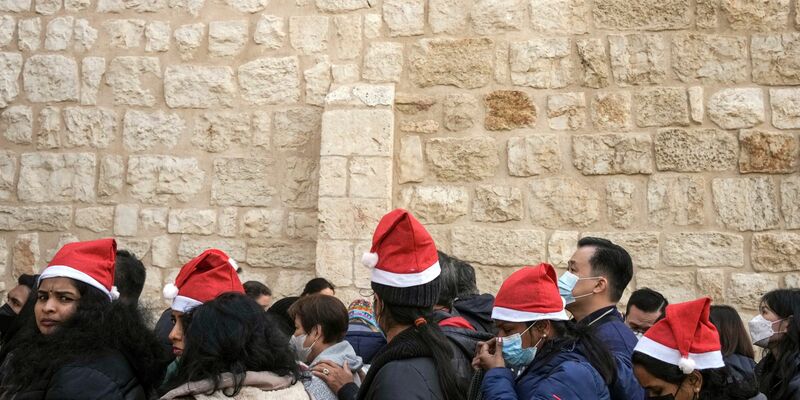 Heiligabend im vergangenen Jahr: Touristen - einige mit Weihnachtsmützen - stehen in Bethlehem vor der Geburtskirche Schlange. - Foto: Maya Alleruzzo/AP/dpa