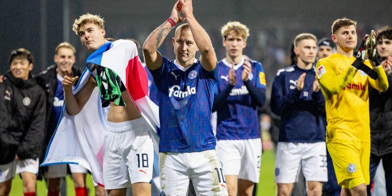 Die Kieler Spieler feierten mit den Anhängern, die nach dem Schlusspfiff auf das Spielfeld gestürmt waren. - Foto: Axel Heimken/dpa