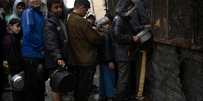 Kinder warten in Rafah auf die Ausgabe von Lebensmitteln. - Foto: Fatima Shbair/AP/dpa