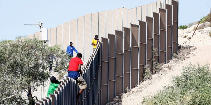 Migranten klettern über einen Zaun auf der Insel Lampedusa. - Foto: Cecilia Fabiano/LaPresse via ZUMA Press/dpa