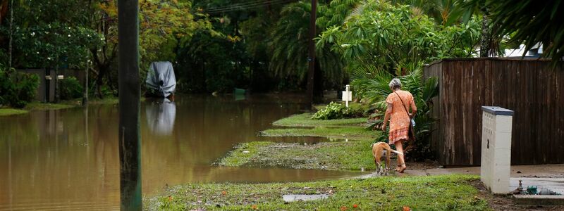 Eine Frau spaziert mit ihrem Hund durch das Hochwasser im Vorort Holloways Beach in Cairns. - Foto: Joshua Prieto/AAP/dpa
