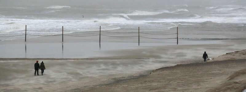 Strandspaziergänger trotzen dem starken Wind auf der Insel Wangerooge. - Foto: Peter Kuchenbuch-Hanken/-/dpa