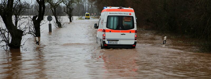 Ein Krankenwagen fährt über eine von Hochwasser überflutete Straße nach Windehausen in Thüringen. - Foto: Stefan Rampfel/dpa