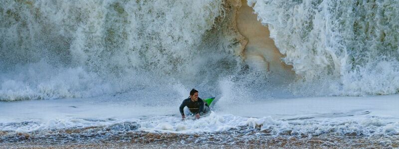 Ein Surfer taucht in Seal Beach aus den Wellen auf. - Foto: Damian Dovarganes/AP