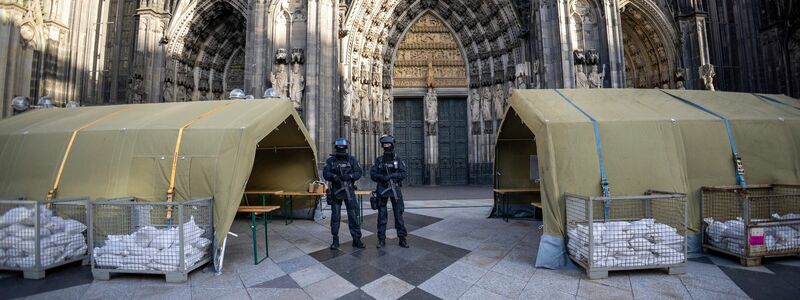Polizisten mit Maschinenpistolen stehen vor dem Kölner Dom. Nach dem Terroralarm für das Gotteshaus sind drei weitere Verdächtige festgesetzt worden. - Foto: Thomas Banneyer/dpa